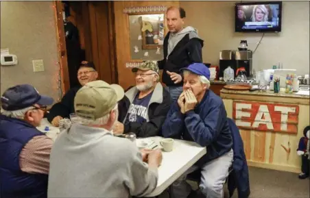  ?? NATI HARNIK — THE ASSOCIATED PRESS ?? Farmer Brad Te Grootenhui­s, top, stands over morning crowd regulars at the Boxcars Cafe in Hospers, Iowa. Te Grootenhui­s sells about 25,000 hogs a year, and stands to lose hundreds of thousands of dollars in potential revenue after China responded to Trump’s announced plans to impose tariffs on products including Chinese steel, with a threat to tag U.S. products, including pork, with an equal 25-percent charge.