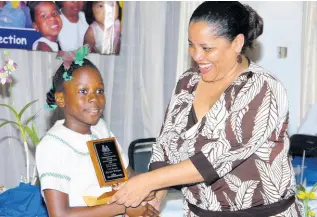  ?? FILE ?? Eight-year old Lori-Ann Mullings of Excelsior Primary School receives an award from Alison McLean, then CEO of the Child Developmen­t Agency, at the National Child Month Committee 2007 Community Service Awards ceremony at the Alhambra Inn in Kingston.