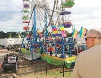  ?? THE ASSOCIATED PRESS ?? Baileyton police Officer Kenneth Bitner, right, and law enforcemen­t cordon off the area surroundin­g the Ferris wheel Monday after three people fell from the ride during a county fair in Greenville, Tenn.
