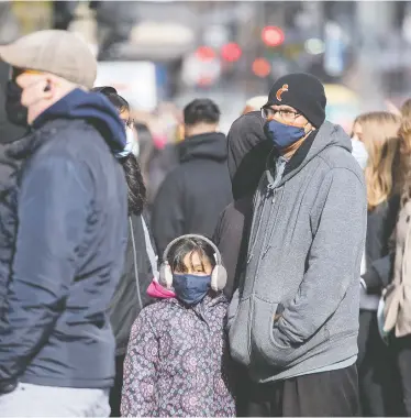  ?? GRAHAM HUGHES / THE CANADIAN PRESS ?? Shoppers in face masks wait to enter a store in Montreal. Vaccines against COVID-19 are not expected until late 2021.