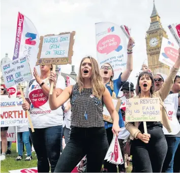  ??  ?? > Protesters chant and wave placards in Parliament Square, during a protest against a Government pay cap