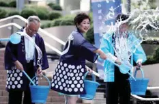  ??  ?? Tokyo Governor Yuriko Koike splashes water during a water sprinkling event called Uchimizu to cool down the area, in Tokyo on Monday. — AFP