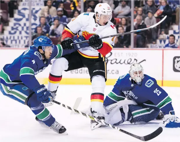  ?? — CP FILES ?? Canucks defenceman Michael Del Zotto pushes Flames centre Mikael Backlund away from goalie Jacob Markstrom’s doorstep during opening night action at Rogers Arena Wednesday. The Canucks beat Calgary, 5-2, before heading out on a gruelling six-game road swing.