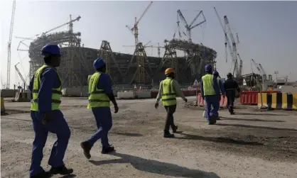  ?? Photograph: Hassan Ammar/AP ?? Workers walk to the Lusail Stadium, one of the 2022 World Cup stadiums in Qatar.