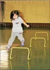  ?? MARTHA GEHRINGER — FOR DIGITAL FIRST MEDIA ?? First grader Ashlyn Griech jumps a hurdle during gym class.