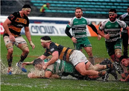  ?? GETTY IMAGES ?? Fraser Armstrong, of Manawatu¯ , is tackled by Chris Gawler amid the mud and water at the Arena.