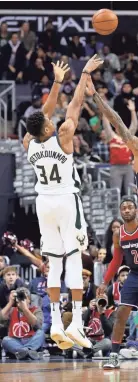  ?? GETTY IMAGES ?? Giannis Antetokoun­mpo hits a three-point shot over the Wizards' Kelly Oubre Jr. last week.