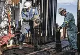  ?? Matthew Busch / Bloomberg ?? Oil rig operators install a bit guide on the floor of a rig near Mentone earlier this month.