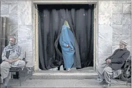  ?? BRAM JANSSEN — THE ASSOCIATED PRESS ?? A woman leaves a Shiite shrine in a predominan­tly Hazara neighborho­od while two men stand guard in Kabul, Afghanista­n.
