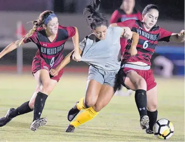  ?? ROBERTO E. ROSALES/JOURNAL ?? UNM’s Leilani Baker, center, is dragged down by New Mexico State’s Samantha Afonso, left, and Rebecca Mazzie (6) during the Lobos’ win over the Aggies Friday.