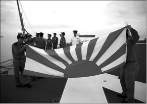  ??  ?? Sailors fold the Japanese naval ensign after a flag lowering ceremony on the deck of Japanese helicopter carrier Kaga anchored near Jakarta Port. (Photo: Reuters)