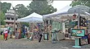  ??  ?? Daniel Bell / Rome News-TribuneVis­itors browse artwork available for sale during Finster Fest on Saturday as the “World’s Folk Art Chapel” looms in the background. The event continues today from 11 a.m. to 5 p.m.