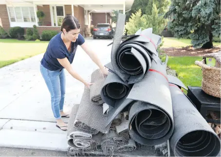  ?? JASON KRYK ?? Jennifer Zazula stacks rolls of carpet removed from the basement of her Windsor home, which was flooded during Tuesday’s storm.