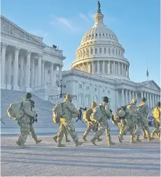  ?? — AFP file photo ?? Members of the US National Guard walk past the US Capitol in Washington, DC, ahead of the 59th inaugural ceremony for Biden and vice-president-elect Kamala Harris.