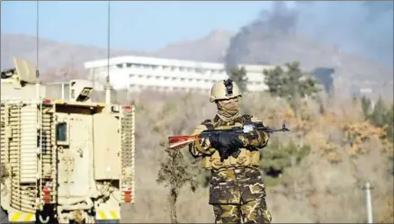  ?? WAKIL KOHSAR/AFP ?? Afghan security personnel standing guard as smoke billows from the Interconti­nental Hotel during a fight between gunmen and security forces in Kabul on January 21.