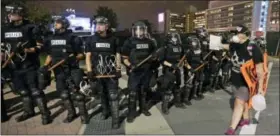  ?? CHUCK BURTON — THE ASSOCIATED PRESS ?? A protester walks in front of a line of police officers blocking the access road to I-277 on the third night of protests in Charlotte, N.C. Thursday, following Tuesday’s fatal police shooting of Keith Lamont Scott.