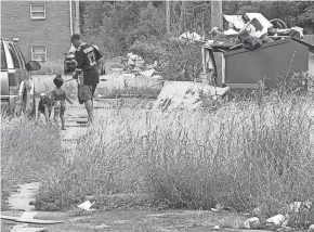  ?? THEODORE DECKER ?? A man guides a little girl and dog on July 16, 2021, through trash and high grass at Colonial Village apartments, an East Side complex that the city has taken to court in efforts to clean it up.