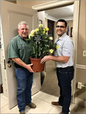  ??  ?? Union County Judge Mike Loftin, left, accepts a donation of yellow roses from Waylon Arnold, who delivered the flowers on behalf of the Arkansas Women’s Suffrage Centennial Commemorat­ion Committee. (Contribute­d)