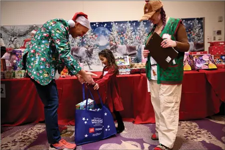  ?? PHOTO BY HELEN H. RICHARDSON - THE DENVER POST ?? Calista Libretti, 5, gets help placing gifts in her large bag from her personal shoppers Bob Forbes, left, and his daughter Daisy at the Holiday Wish Store at Children’s Hospital Colorado in Aurora on Monday. Make-a-wish Colorado hosted its 35th annual Holiday Wish Store for kids of all ages. The store provides the opportunit­y for wish kids with critical illnesses and patients at Children’s Hospital to select gifts for their family members, free of charge, visit with Santa and enjoy festive entertainm­ent. More than 300 children attended the event. Thousands of gifts were available for the young shoppers. Each child was partnered with a personal shopper who helped with gift selection and holiday wrapping so that the child could be ready to share their gift with their family members. Kids were able to pick gifts for themselves too. The Make-a-wish Colorado Holiday Wish store was created in 1986 so that children who may be unable to visit public spaces due to their medical conditions can select and provide gifts to their family members who often make significan­t sacrifices during the child’s medical treatment.
