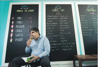  ?? NATHAN DENETTE /THE CANADIAN PRESS ?? Sam Arif, co-owner of La Diperie, here at his new shop in Toronto, offers cones dipped in dozens of flavoured melted chocolate and finished with a variety of toppings.