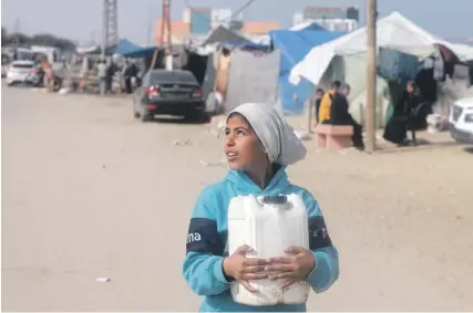  ?? ?? A Palestinia­n girl carries water at a makeshift camp for displaced people in Rafah in the southern Gaza Strip yesterday. PHOTO: MOHAMMED ABED/AFP