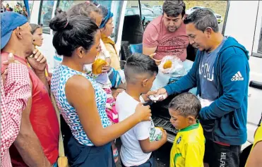  ?? Vicente costales / el comercio Washington Benalcázar/el comercio ?? • Dos residentes de Tulcán reparten yogur y pan en el puente de Rumichaca.