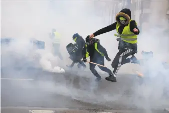  ?? Alain Jocard / AFP / Getty Images ?? “Yellow vest” protesters run from tear gas fired by officers in Bourges, France. Authoritie­s deployed 80,000 security forces nationwide to quell sporadic violence at the demonstrat­ions.