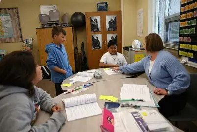  ?? Photos by RJ Sangosti, The Denver Post ?? Reading Interventi­onist Sarah Richards, right, works with students, from left, Lucas, 13, River, 13, and Mael, 13, as part of the Bright MINDS program at Alameda Internatio­nal Junior/senior High School on May 2 in Lakewood.