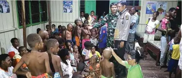  ?? POLDA PAPUA FOR JAWA POS ?? SAUDARA SETANAH AIR: Para orang tua bersama bayi mereka antre untuk mendapatka­n pengobatan campak dan gizi buruk di Kabupaten Asmat pada Sabtu (20/1). Foto kiri, anggota TNI-Polri dan petugas medis mengecek kondisi kesehatan anakanak Asmat.