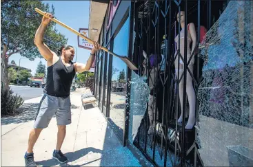  ?? PHOTOS BY SARAH REINGEWIRT­Z – STAFF PHOTOGRAPH­ER ?? Carlos Castillo cleans up broken glass at Excitement in Woodland Hills after dozens of businesses had their windows shot out early Wednesday morning along Ventura Boulevard from Encino to Woodland Hills on Wednesday.