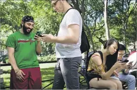  ?? Drew Angerer Getty Images ?? MEDICAL STUDENTS Jag Chilana, left, and Scott Kobner play “Pokemon Go” in New York. The craze is drawing players outside, with eyes glued to their phones.