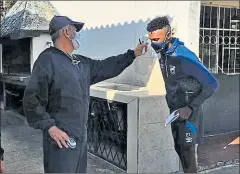  ??  ?? • Francisco Naranjo, médico de U. Católica, toma la temperatur­a a un futbolista, en el complejo La Armenia.