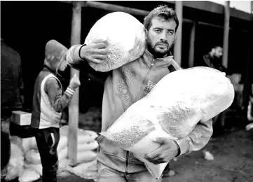  ??  ?? A Palestinia­n man carries food supplies at a United Nations food distributi­on centre in Al-Shati refugee camp in Gaza City in this file photo. — Reuters photo