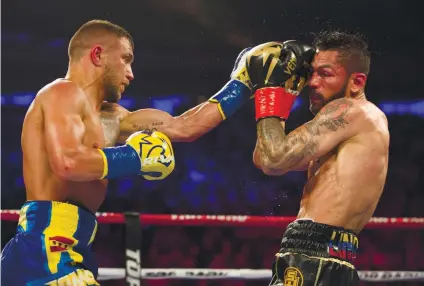  ?? AP FOTO/KEVIN HAGEN ?? THREE IN 12. Vasiliy Lomachenko (left) survived a sixth-round knockout and stopped Jorge Linares in the 10th to win a world title in a third weight division in just his 12th fight.