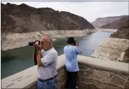  ?? JOHN LOCHE—ASSOCIATED PRESS ?? People take pictures of Lake Mead near Hoover Dam at the Lake Mead National Recreation Area, Friday, Aug. 13, 2021, in Arizona. The bathtub ring of light minerals shows the high water mark of the reservoir which has fallen to record lows.