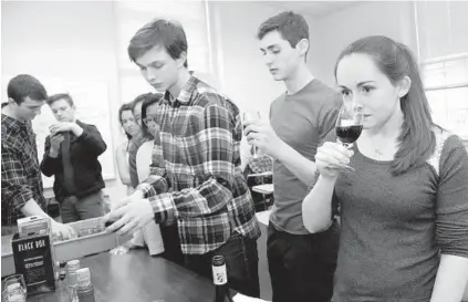  ?? ALGERINA PERNA/BALTIMORE SUN ?? Laura Nugent, far right, examines the smell of wine in a class on fermentati­on taught by Johns Hopkins University graduate student Ben Crane during intersessi­on. Next to her is Louis Hoffenberg, followed by Ronan Perry.