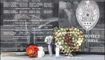  ?? JOHN GASTALDO / SAN DIEGO UNION-TRIBUNE ?? Flowers and candles remain at the San Diego Police Department memorial to fallen officers Friday, the morning after an officer-involved shooting left one officer dead and another wounded.