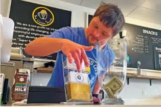  ?? AP PHOTO/HEATHER HOLLINGSWO­RTH ?? Patrick Chapman, 27, prepares for customers Thursday at The Golden Scoop, an Overland Park, Kan., ice cream and coffee shop that employs workers with developmen­tal disabiliti­es, paying them more than minimum wage.