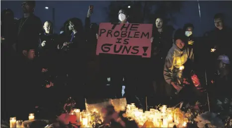  ?? AP PHOTO/ASHLEY LANDIS ?? A man holds a sign during a vigil outside Monterey Park City Hall, blocks from the Star Ballroom Dance Studio, late on Tuesday in Monterey Park, Calif.