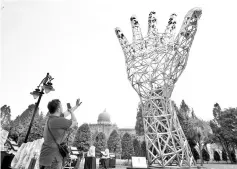  ??  ?? A member of the public seen taking a photo of the 12-metre steel sculpture of a raised hand signifying internatio­nal solidarity in combating corruption. - Bernama photo