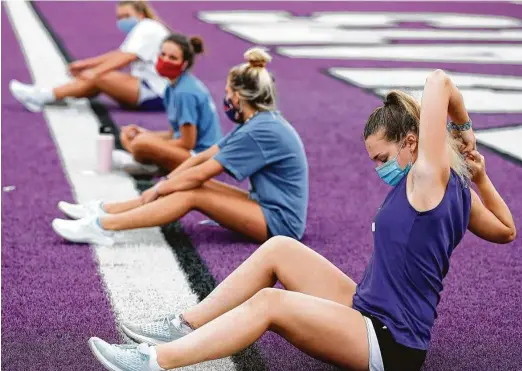  ?? Jason Fochtman / Staff photograph­er ?? Mia Arrington, foreground, stretches as she wears a face mask during a strength and conditioni­ng workout at Willis High School.