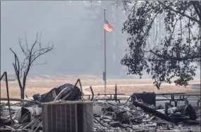  ?? Karl Mondon / Associated Press ?? In this Wednesday photo, the American flag still flies over the remains of the Little Basin Campground visitor center in Big Basin Redwood State Park after the park was ravaged by the CZU Complex fire near Boulder Creek, Calif. In heavily damaged areas, crews were working to restore electricit­y and water so more people could return to their homes.