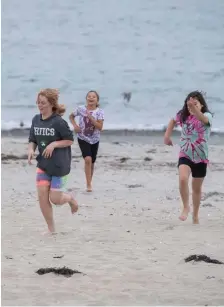 ?? ?? IT’S PERFECT IF YOU’RE MOVING: Cousins Sophae, 12, left, Kayla, 9, center, and Ellie, 8, of Malden run races at Revere Beach in Revere on Sunday, a good day to run around on the beach.