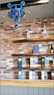  ??  ?? Three antique hay pulleys hang from a 20-foot I-beam and adorn the space above the tasting bar. Bricks from the chimney of a house in Springfiel­d, Mo., provided the perfect spot to hang floating shelves made of 100-year-old wood from a building in Bentonvill­e.