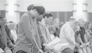  ?? JENNIFER LETT/SUN SENTINEL ?? Members of B’nai Aviv Synagogue in Weston pray along with Rabbi Adam Watstein on Sunday. Watstein told the community, “It may indeed happen again — it's been happening for 2,000 years.”