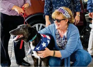  ?? PHOTOS BY RICHARD GRAULICH / THE PALM BEACH POST ?? Debra Cohn embraces Socks, a stray dog who had been shot, abused and abandoned in Iraq, during a reception Thursday at Eastpointe Country Club in Palm Beach Gardens. A State Department contractor befriended the dog in Baghdad and launched a rescue mission that brought him to Florida and his new forever home with the Cohn family.