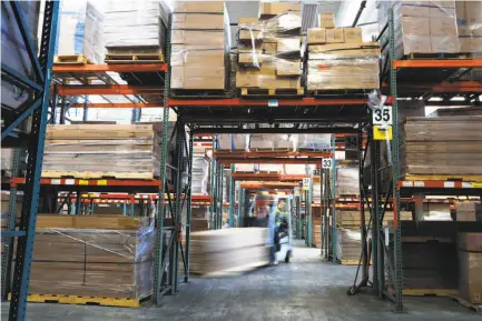  ?? Photos by Michael Macor / The Chronicle ?? At the San Leandro warehouse of mattress company Zinus, workers on forklifts, above, and on foot, below, move products.