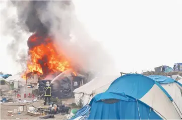  ??  ?? Firefighte­rs extinguish burning makeshift shelters and tents in the ‘Jungle’ on the third day of the evacuation of migrants and their transfer to reception centres in France, as part of the dismantlem­ent of the camp in Calais, France. — Reuters photo
