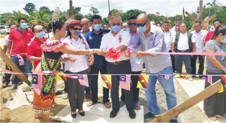  ??  ?? Sikie (centre) cuts the ribbon to symbolical­ly officiate at the ‘Ngentak Rumah Tedung Jambu’ ceremony.