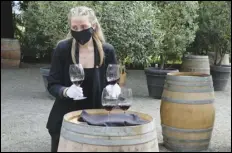  ?? ASSOCIATED PRESS ?? Wine educator Brooke Scheerer serves glasses of 2017 Edizione Pennino Zinfandel to guests Friday at the Inglenook winery in Rutherford, Calif. California wineries started uncorking their bottles and welcoming people back to their tasting rooms.